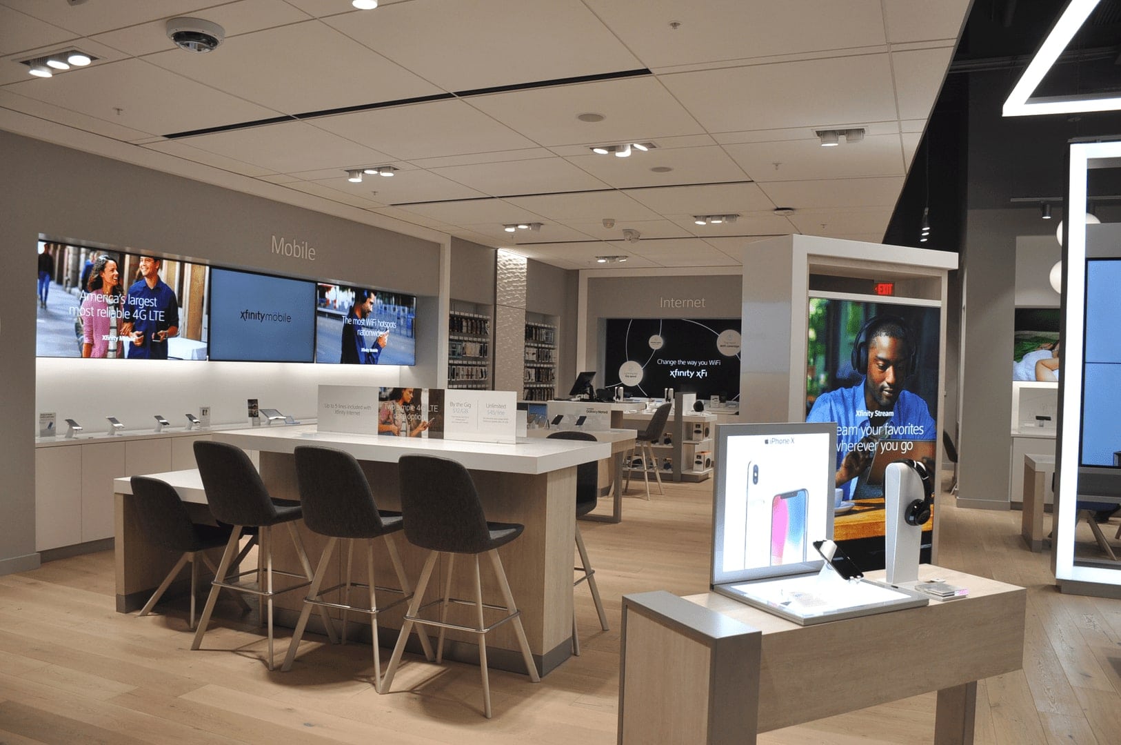 The inside of an Xfinity Comcast store that has a modern table and electronic devices displayed