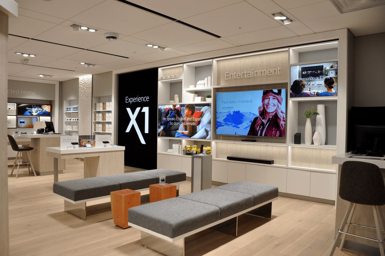 The inside of an Xfinity Comcast store that has modern benches and screens on the wall